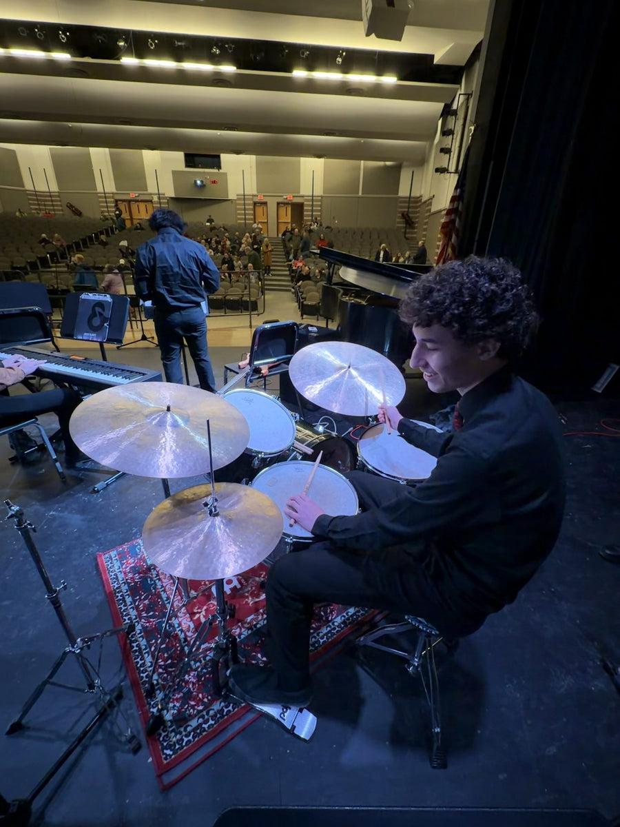 A drum student playing a kit on stage during a performance