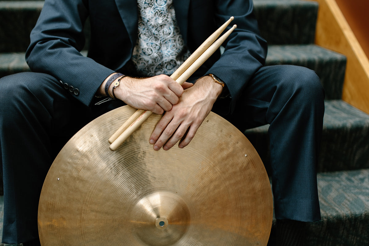 Ryan Barski holding drumsticks and a cymbal