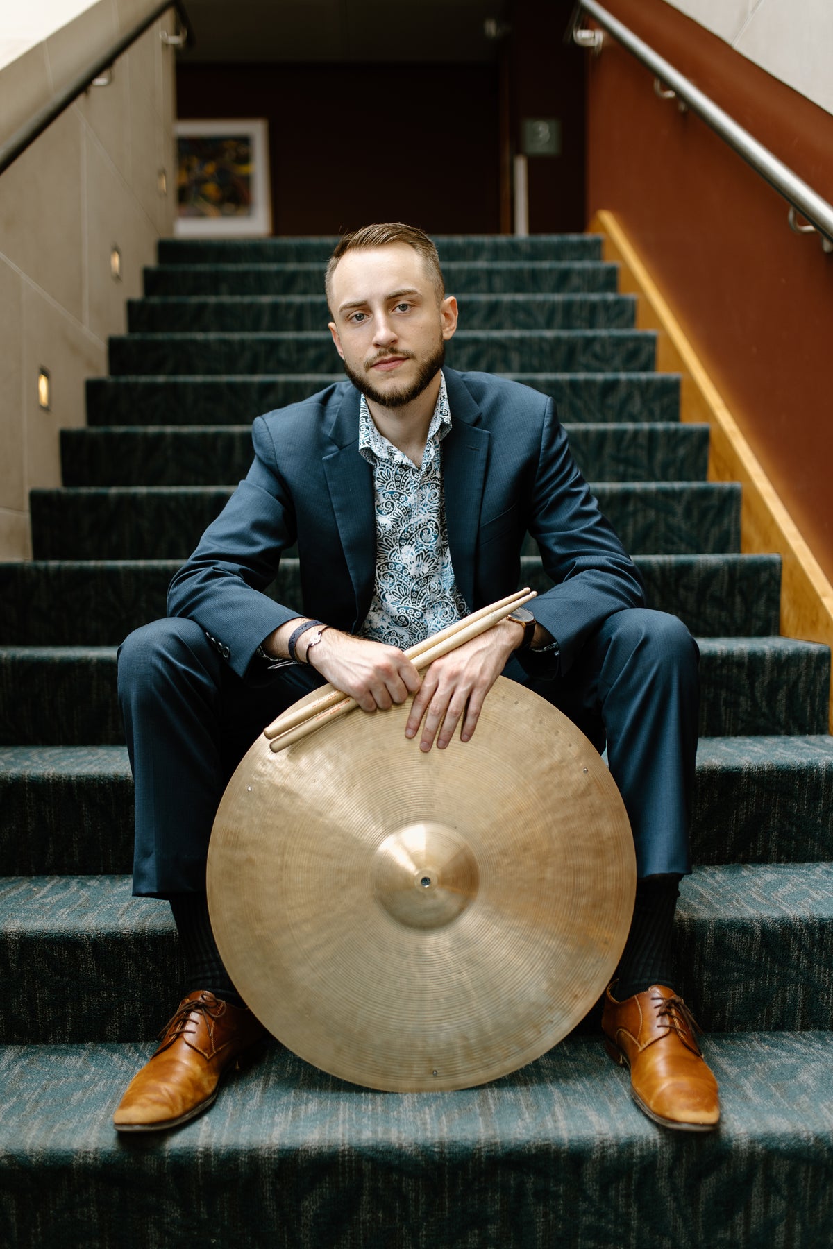 Ryan Barski seated on stairs with a cymbal