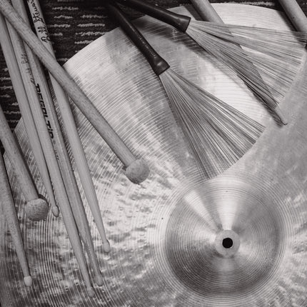 Drumsticks, brushes and a cymbal, black and white