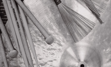 Drumsticks, brushes and a cymbal, black and white
