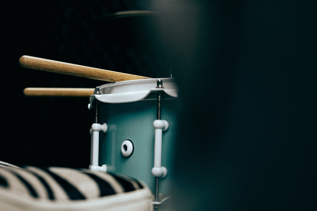 A pair of drumsticks resting on a snare drum head